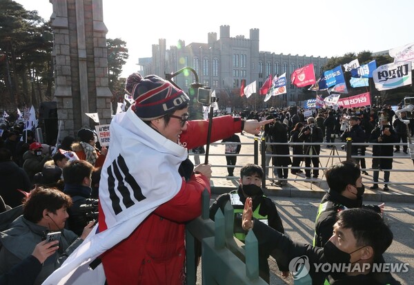 21일 서울 성북구 고려대 교문을 사이에 두고 윤석열 대통령 탄핵에 대한 찬반 집회가 열린 가운데 보수단체 회원이 대치 중 정문을 넘어가려다 제지당하고 있다.=연합뉴스